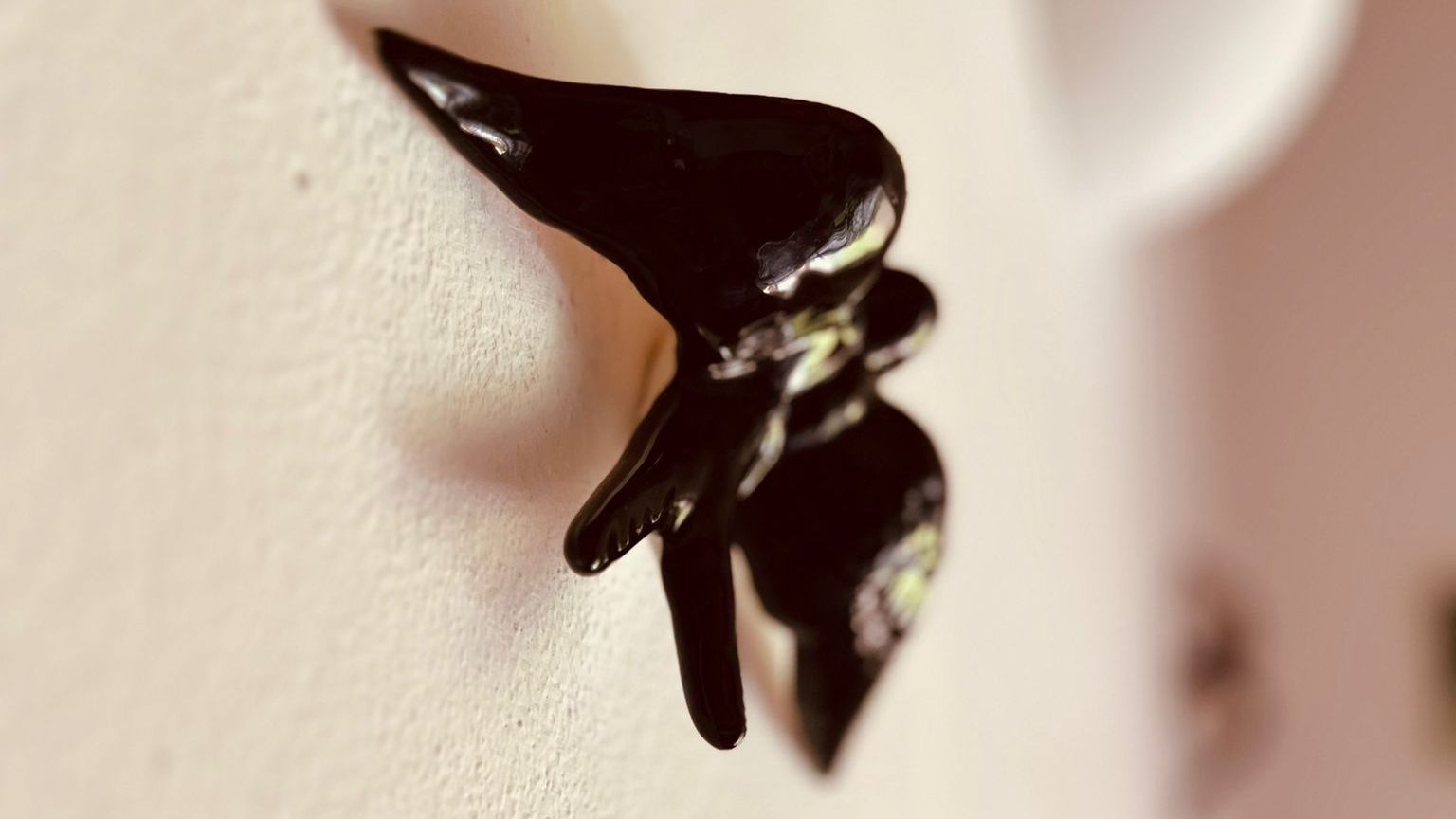 Een close-up van een zwarte oorbel in het oor van een persoon