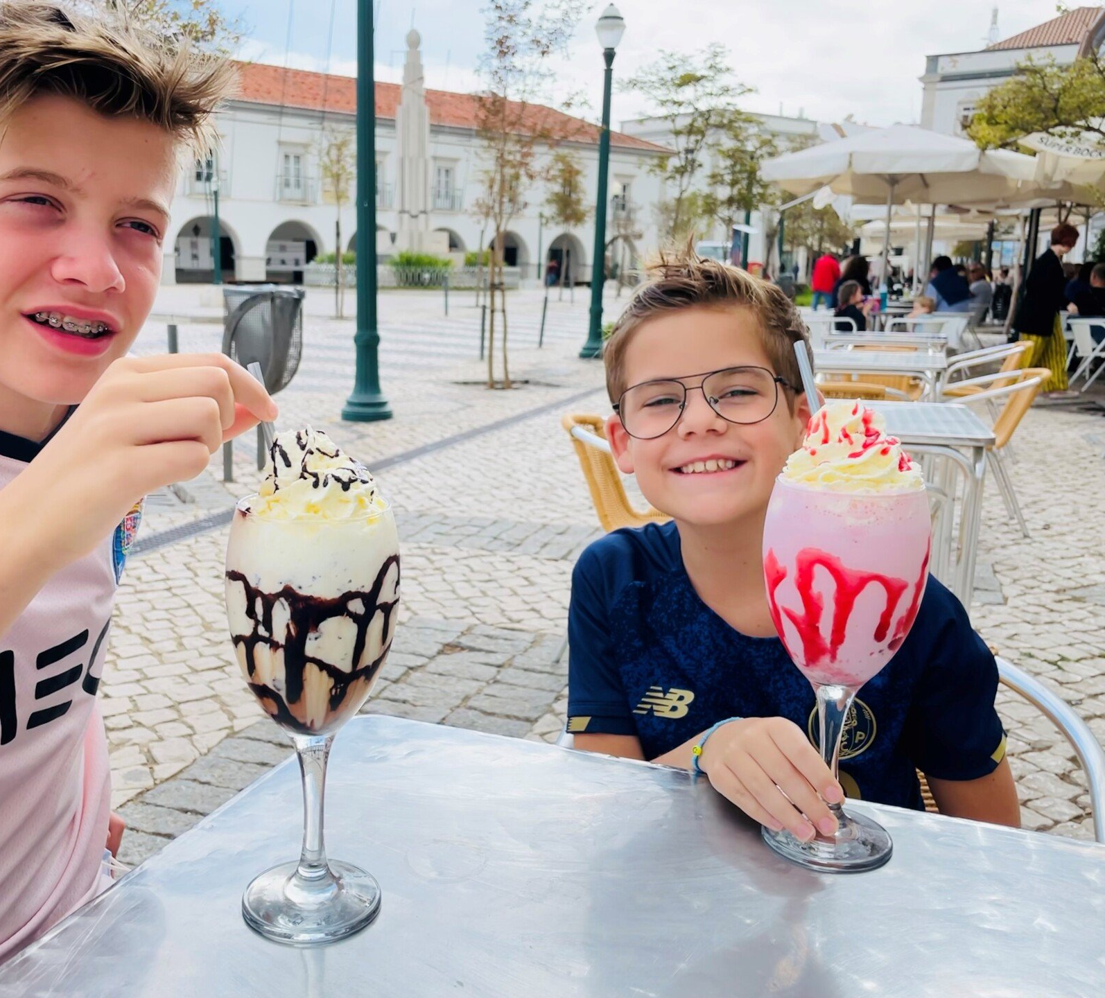 Twee jonge jongens zitten aan een tafel met glazen ijs