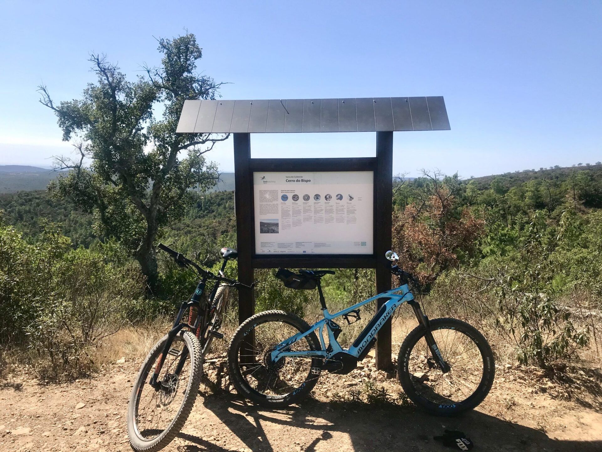 Twee fietsen staan ​​geparkeerd naast een bord bovenop een heuvel.