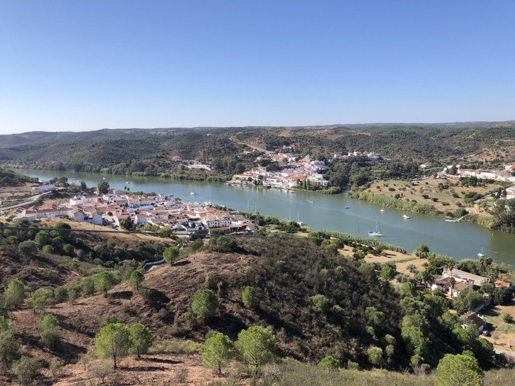 Een luchtfoto van een rivier omgeven door bomen en huizen.