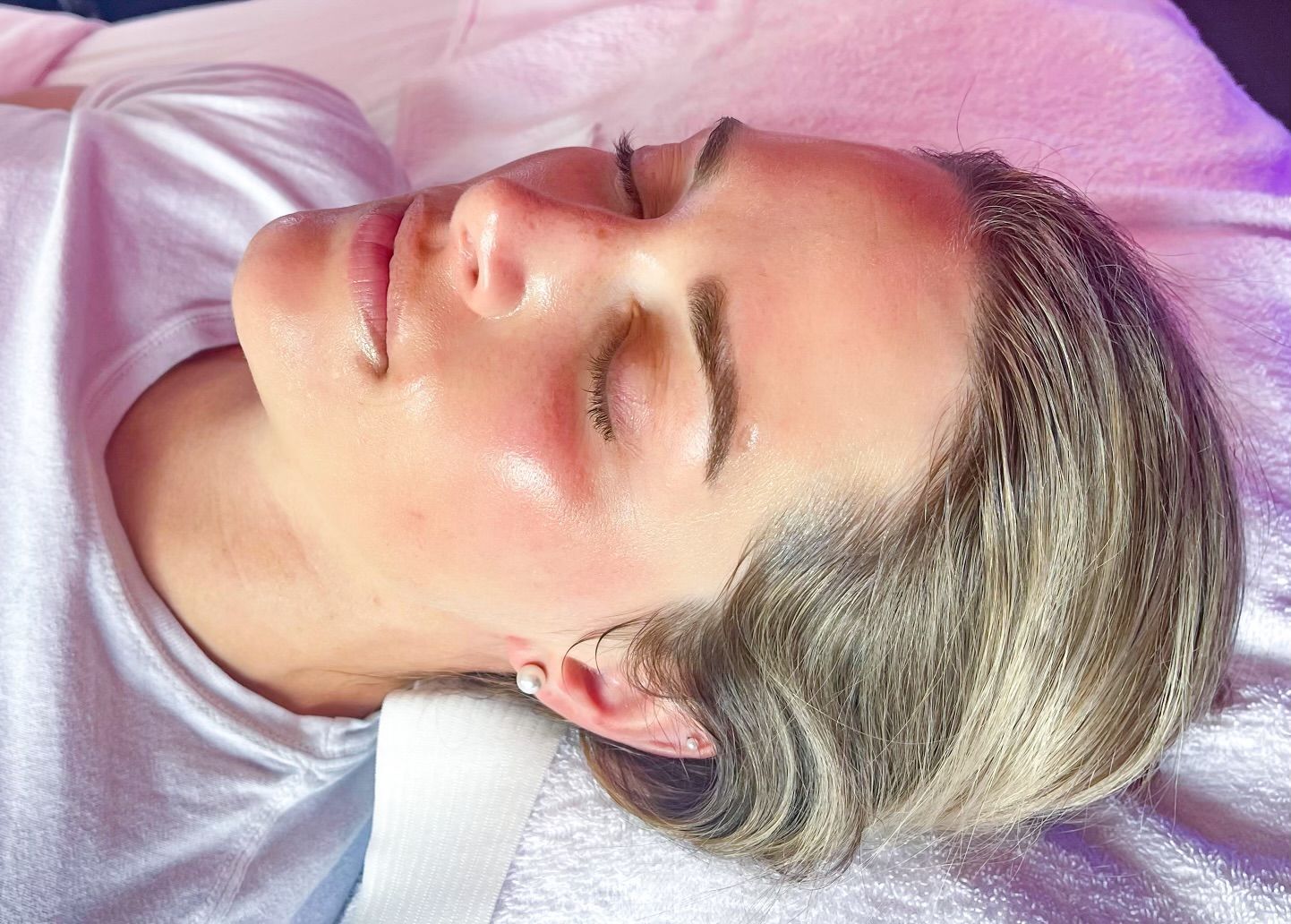 A woman is laying on a bed with her eyes closed.