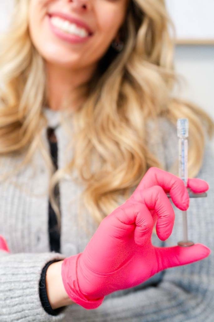 A woman is smiling and touching her face with her hands.