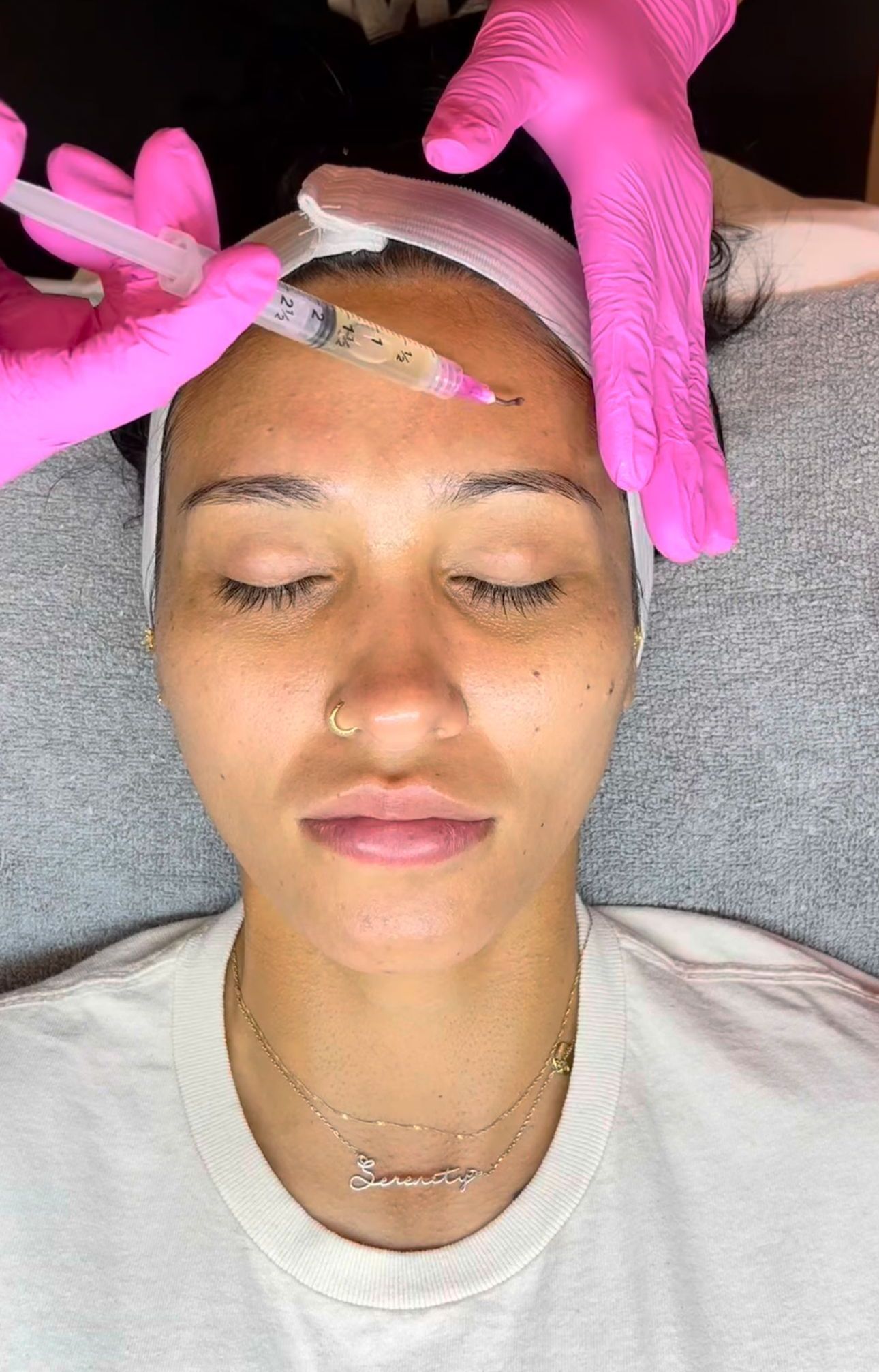 A woman is cleaning her face with a towel.