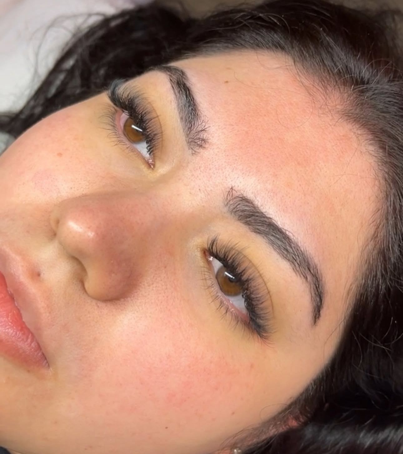 A close up of a woman 's green eye with long eyelashes.