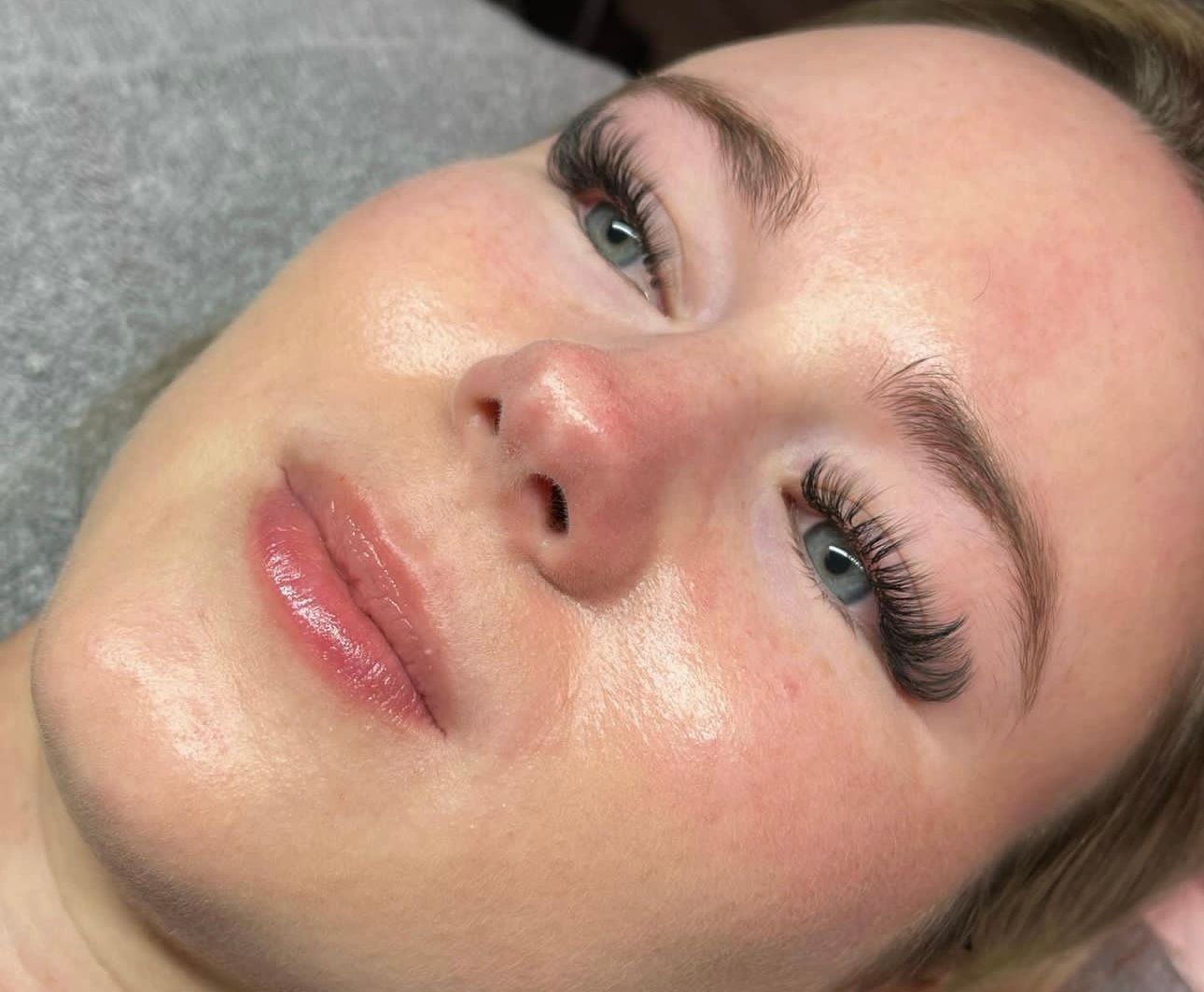 A close up of a woman 's face with long eyelashes and a smile.