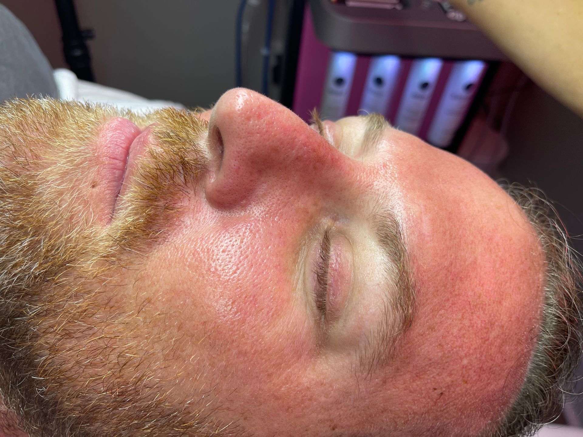 A man with a beard is laying down with his eyes closed.