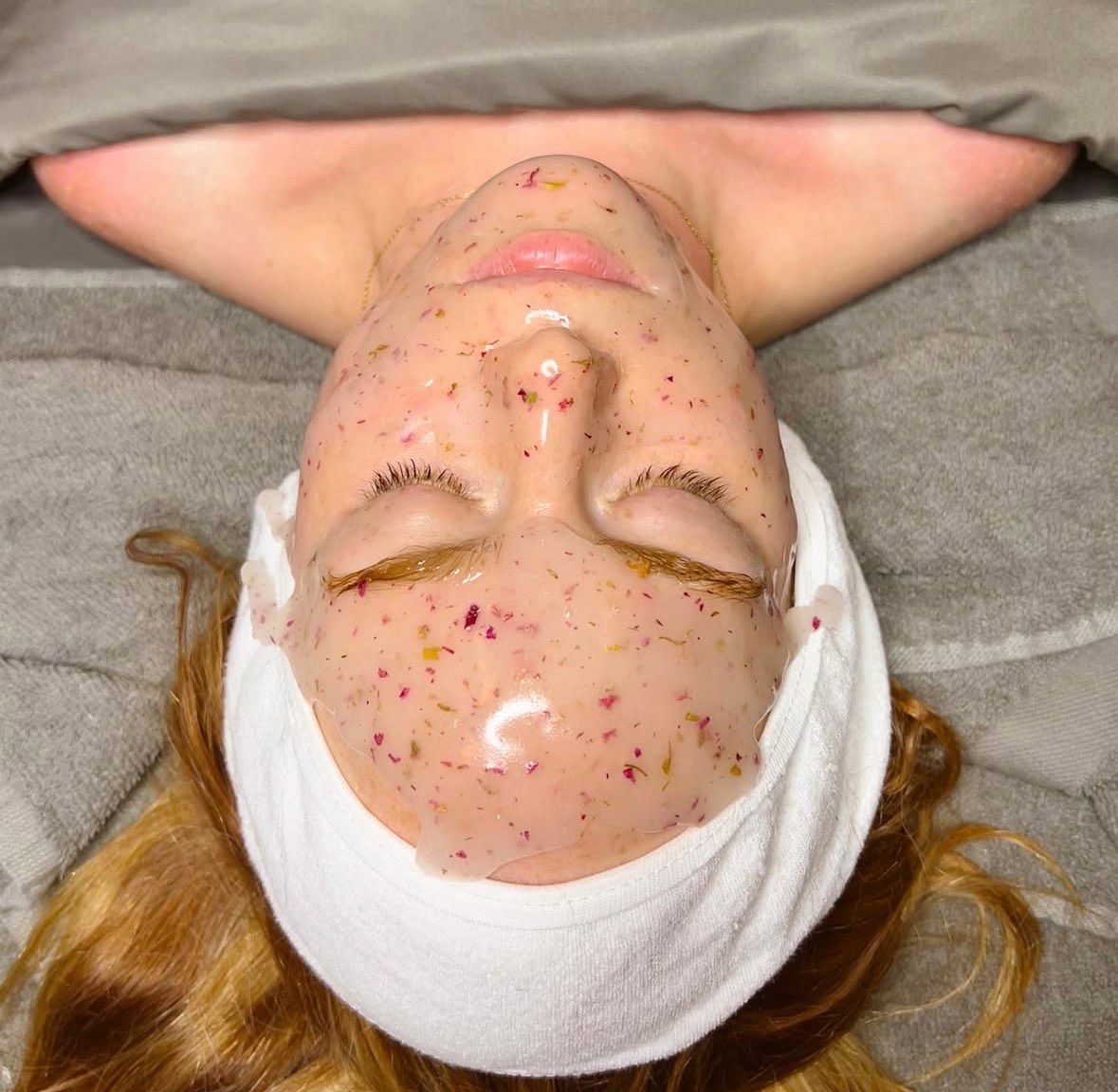 A woman is smiling and touching her face with her hands.