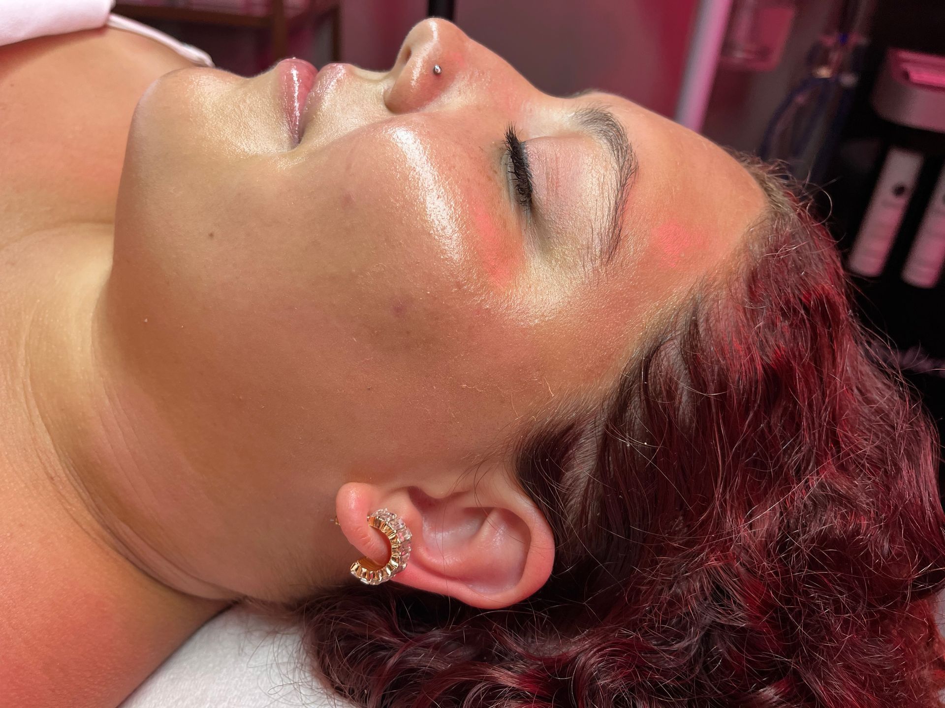 A woman is smiling and touching her face with her hands.