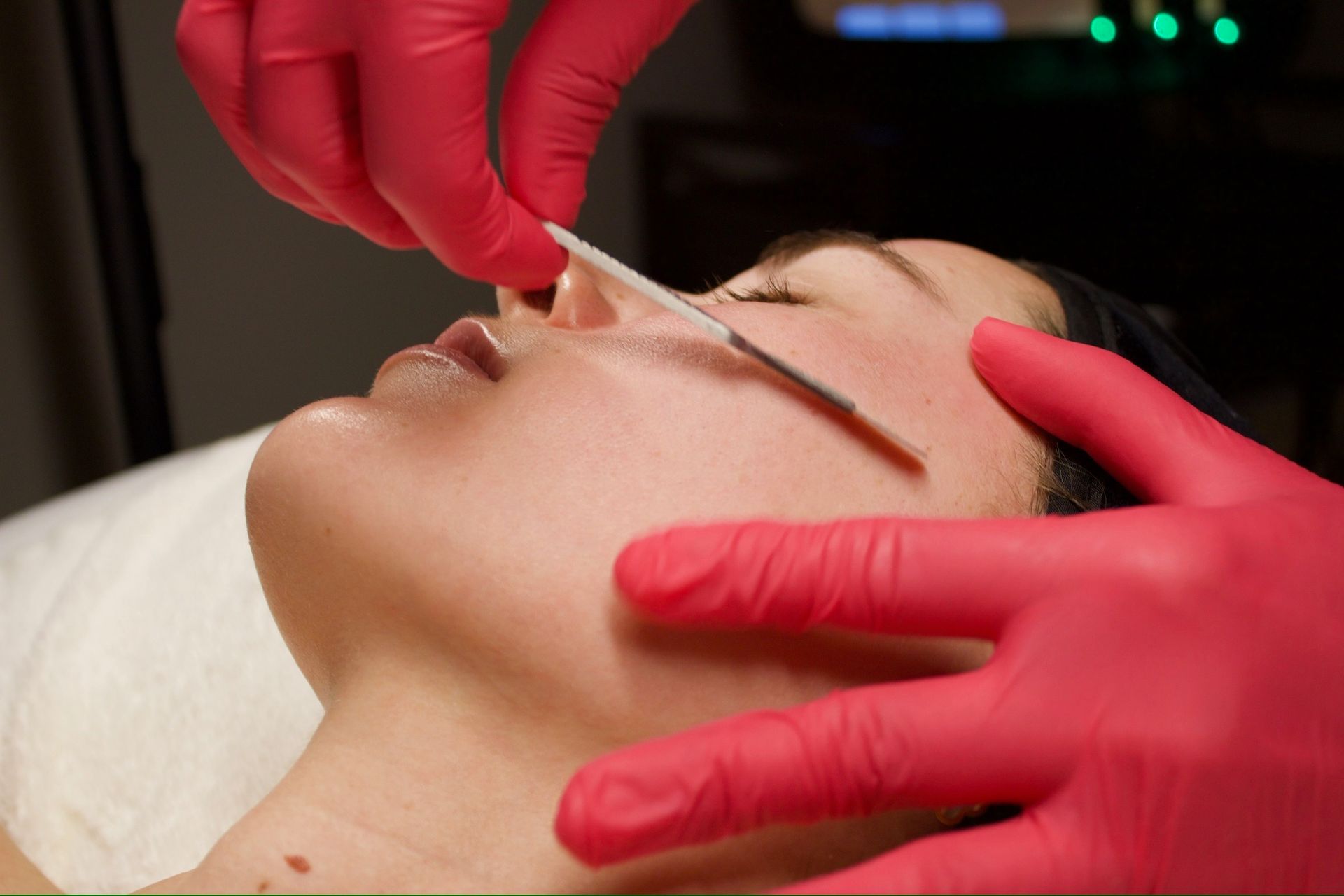 A woman is getting a facial treatment with cotton swabs.