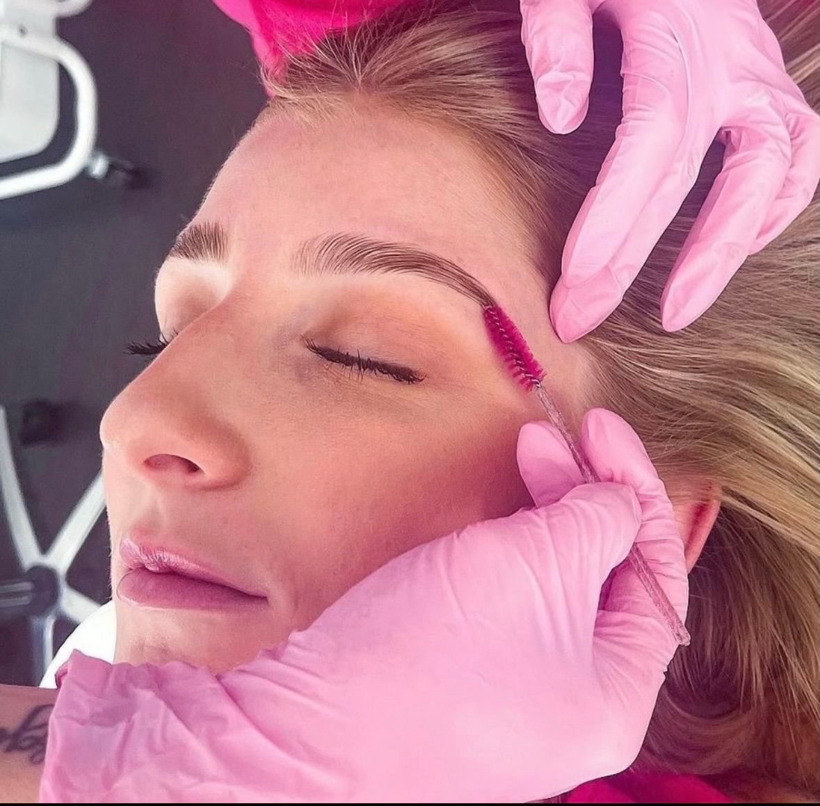 A woman is getting her eyelashes done with tweezers.