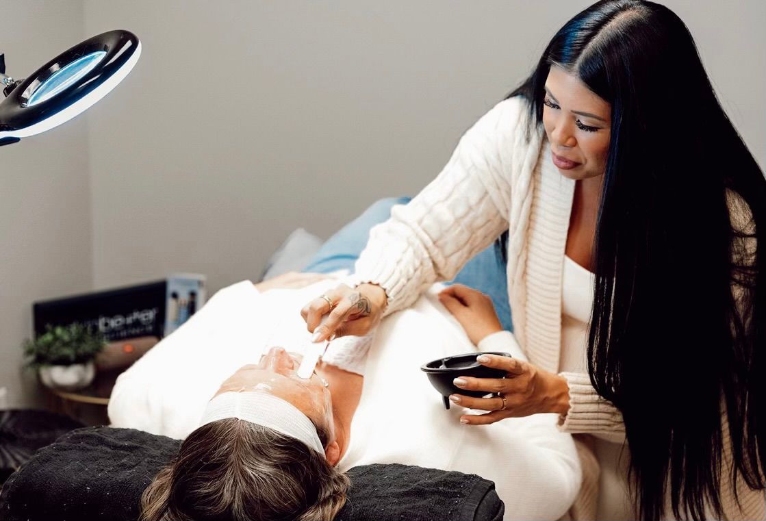 A woman is laying on a bed with steam coming out of her face.