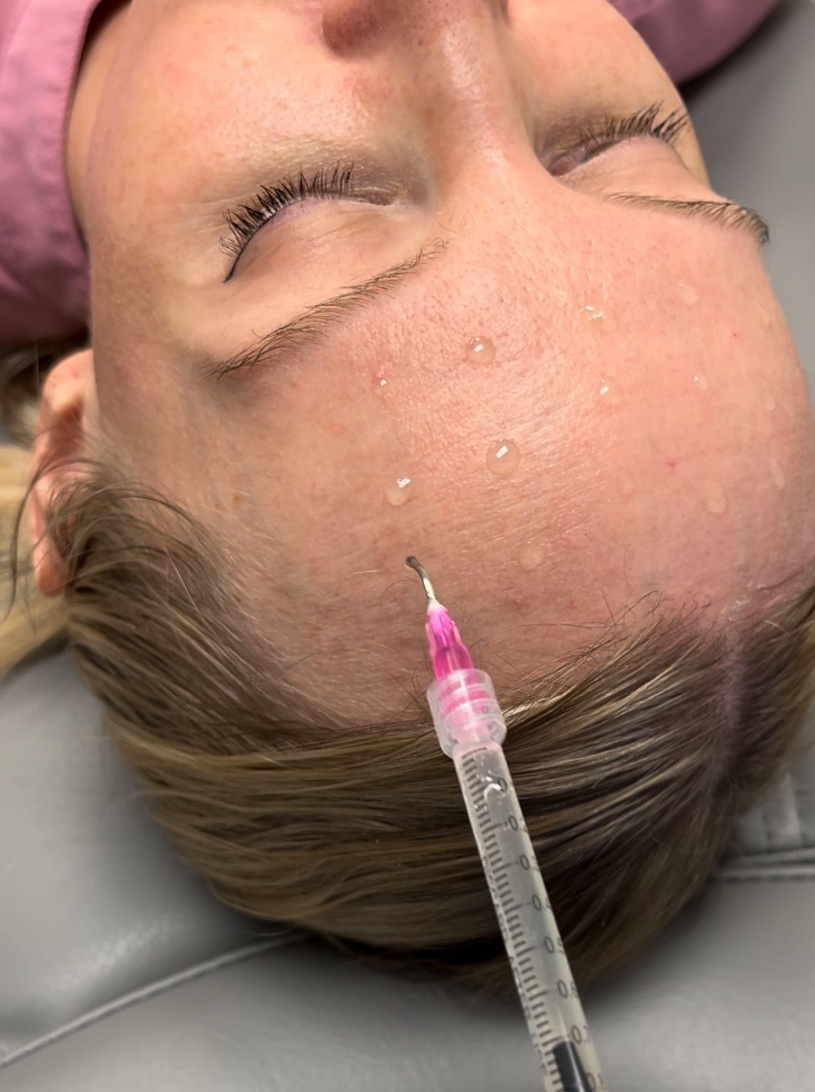 A woman is getting a facial treatment with a brush on her face