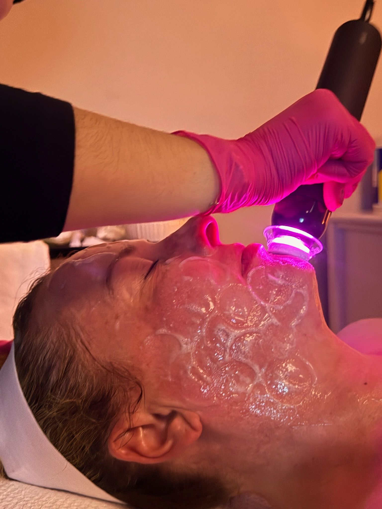 A woman is applying cream to her face with her eyes closed.