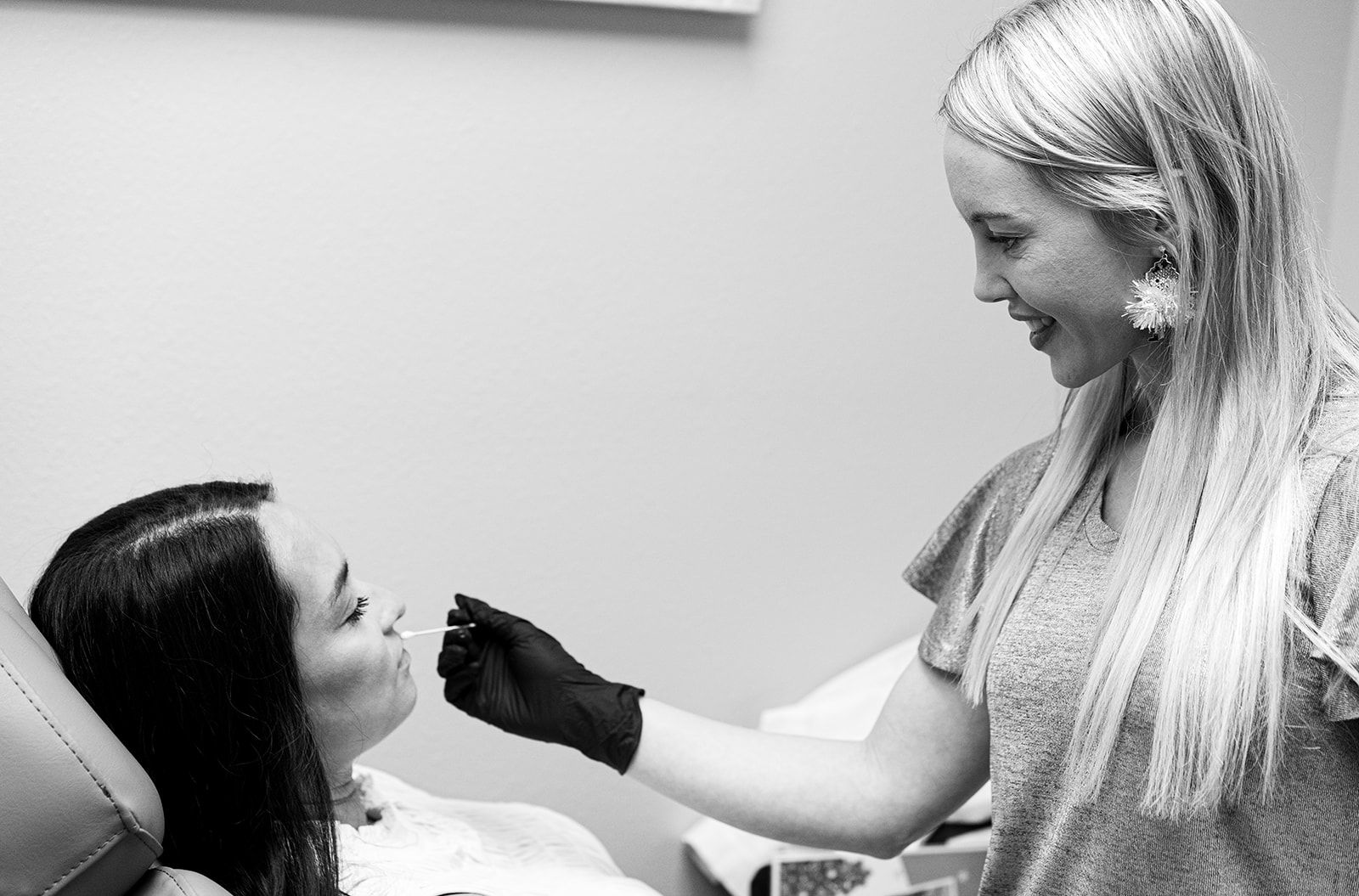 A woman is smiling and touching her face with her hands.