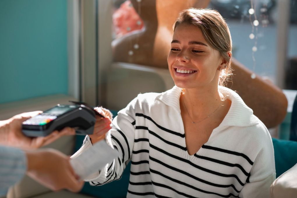 A woman in a striped sweater is paying with a credit card.