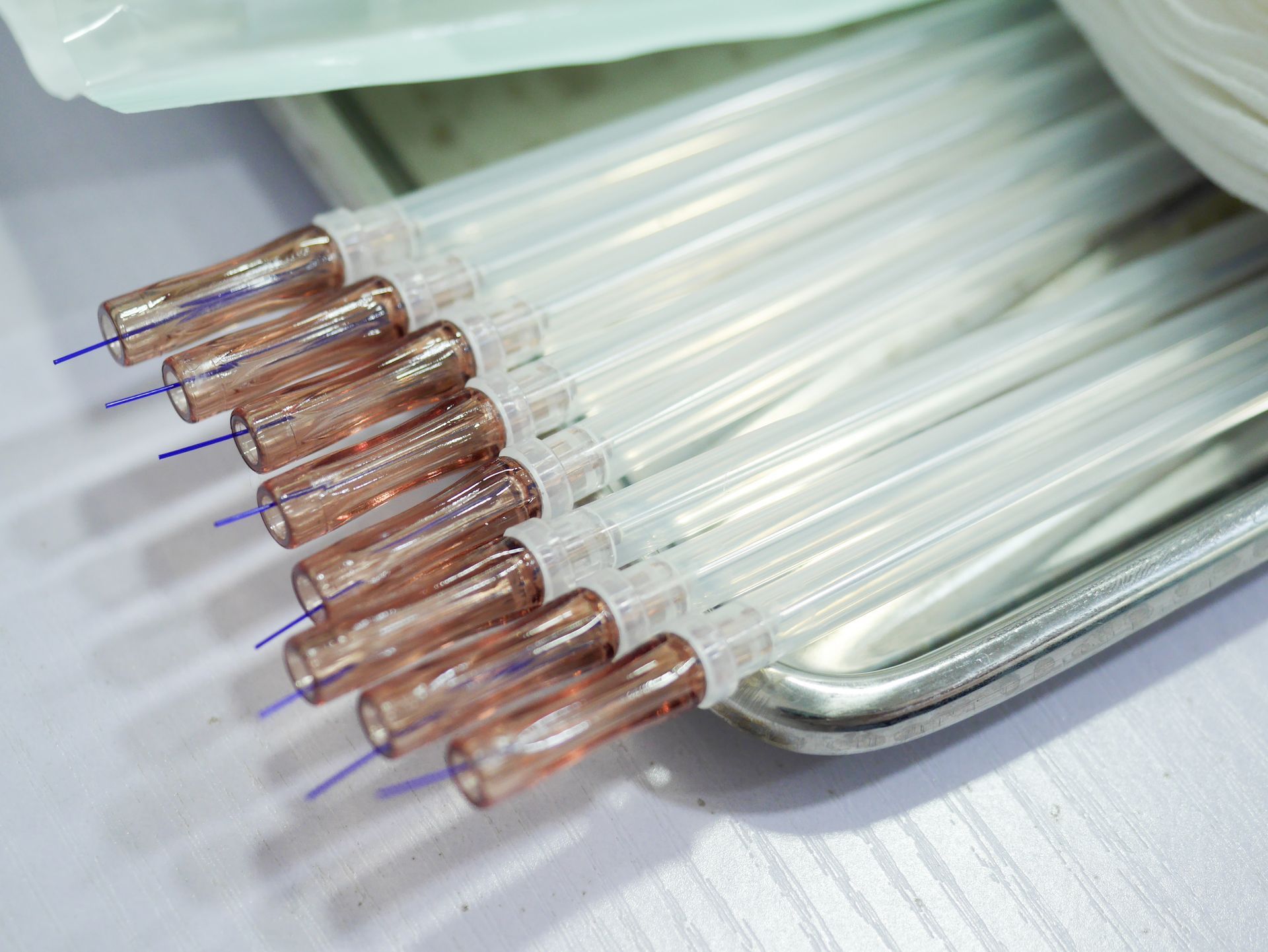 A bunch of syringes sitting on top of a metal tray on a table.