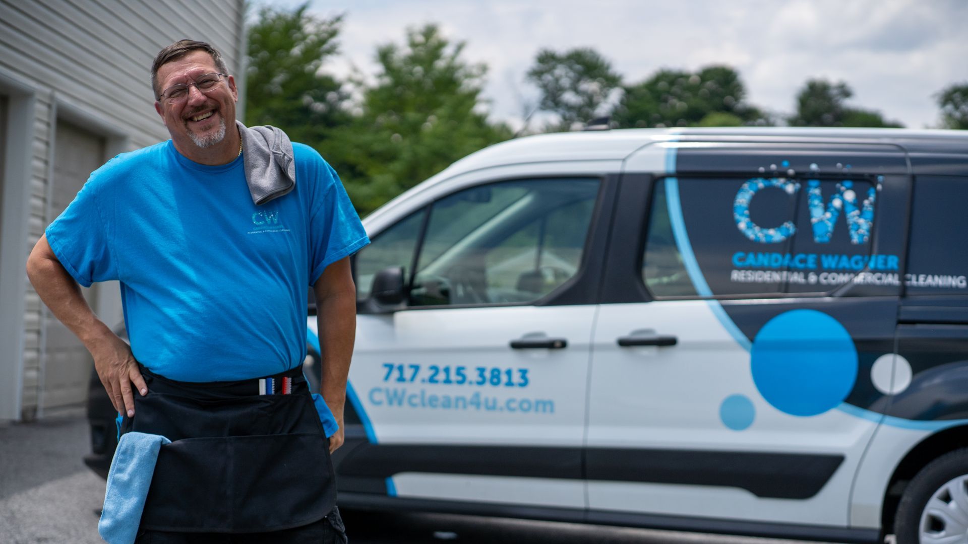 A man in a blue shirt is standing next to a white van.