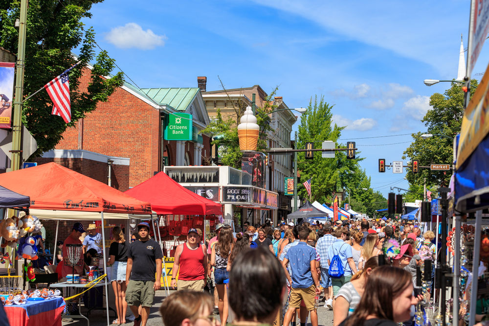 A crowd of people are walking down a street at a festival.