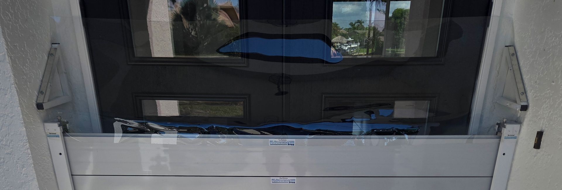 A modern garage door with glass windows reflects the outside environment.