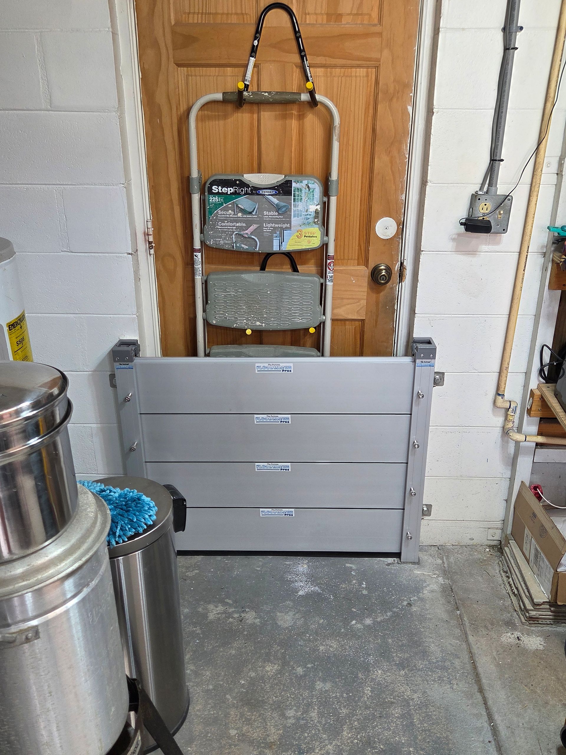 A ladder is hanging on a door next to a flood barrier.