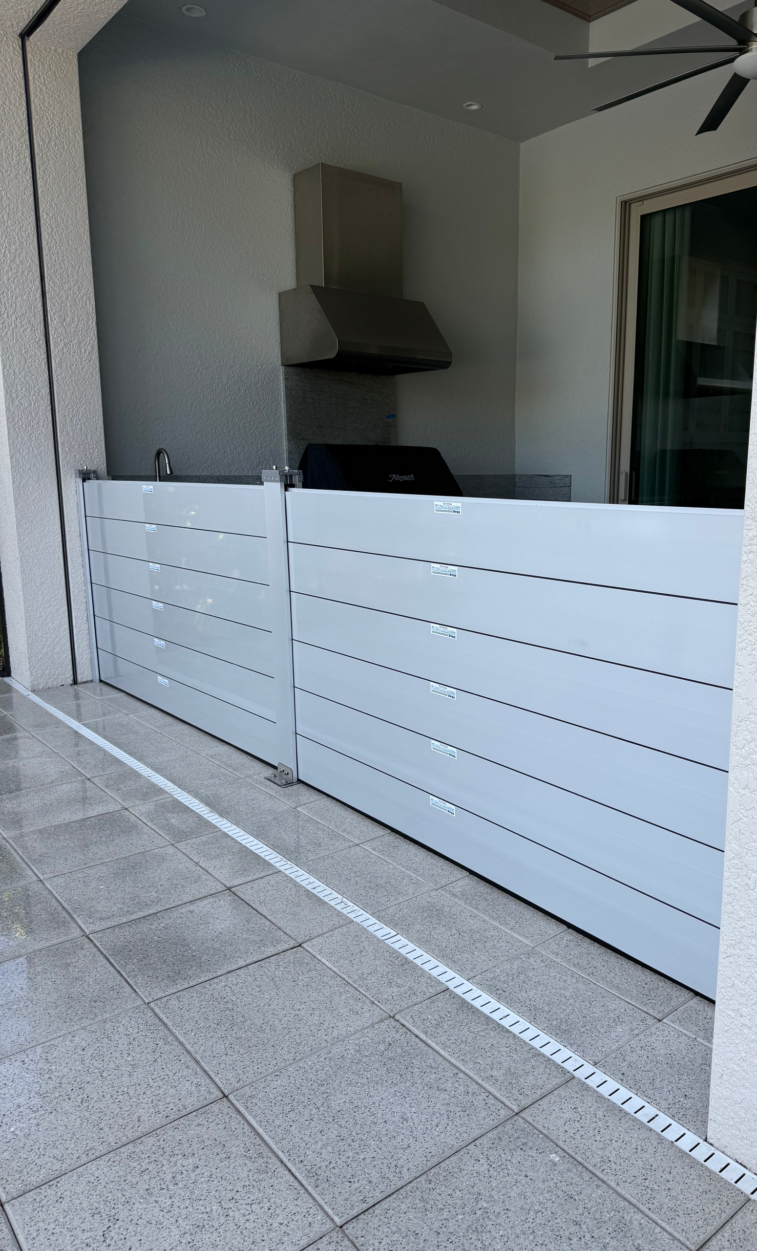 A white fence is sitting on a tiled floor next to a kitchen.