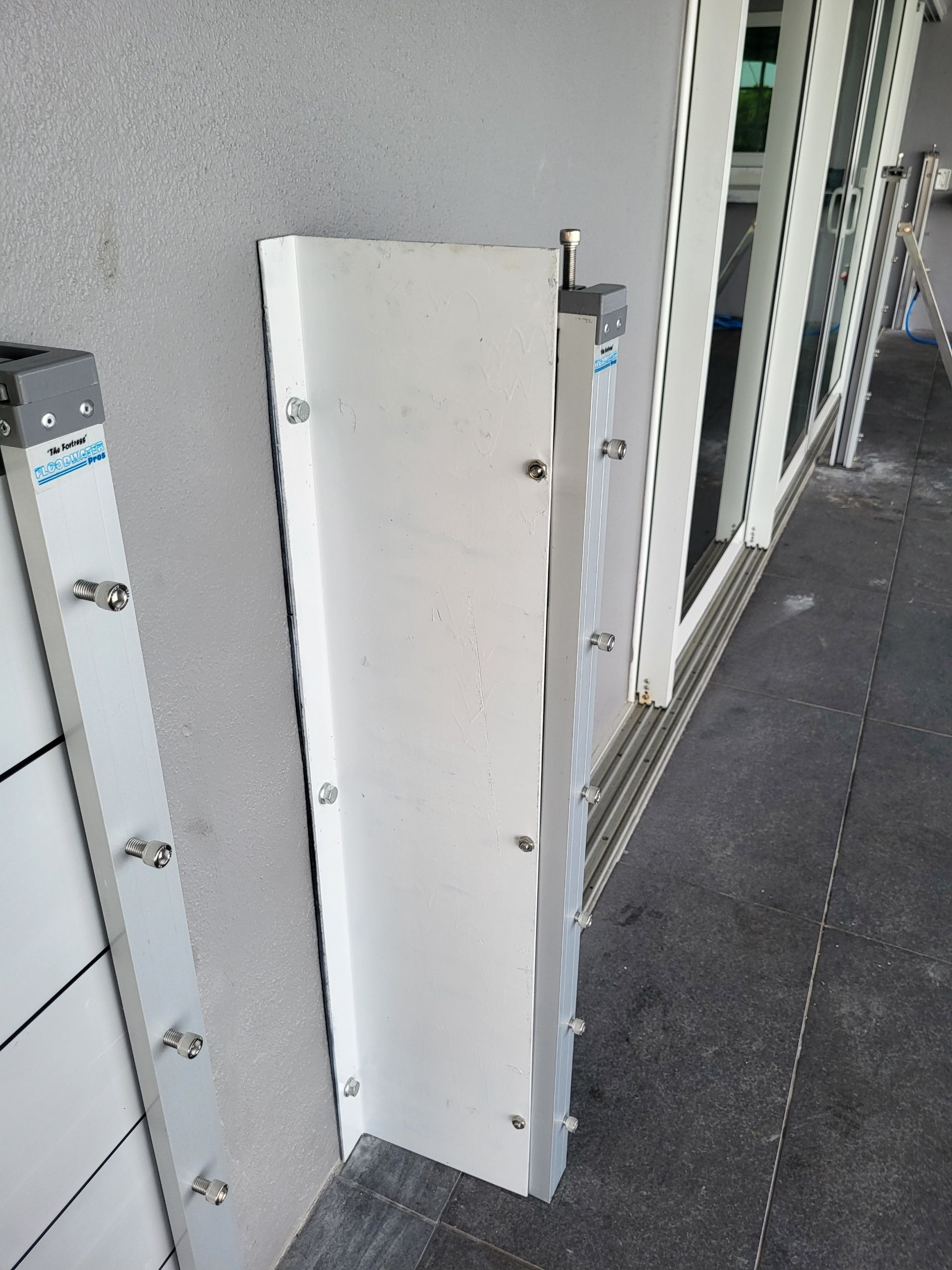 A white shelf is sitting on the side of a building next to a door.