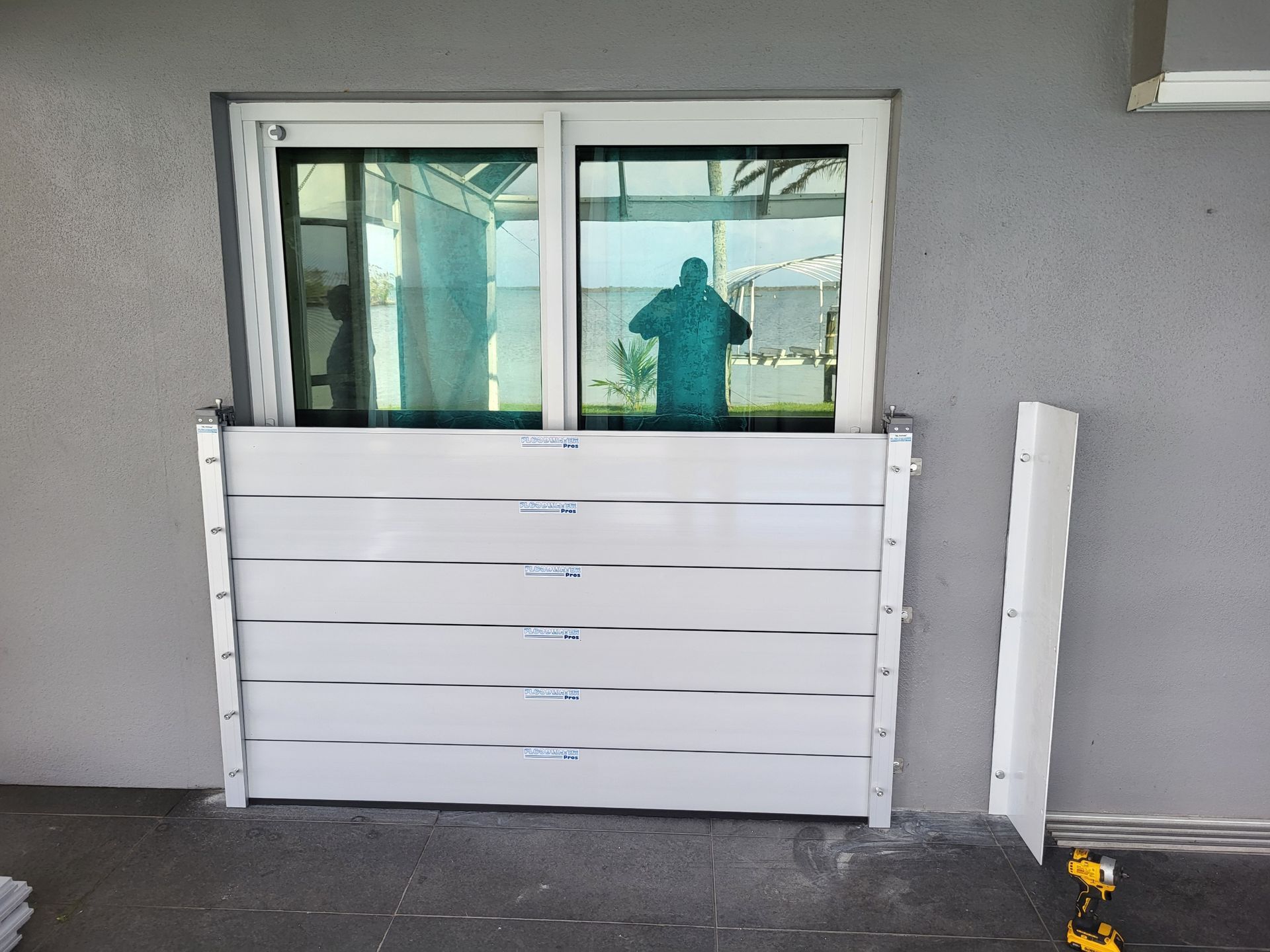A man is standing in front of a window with a reflection of him in the window.