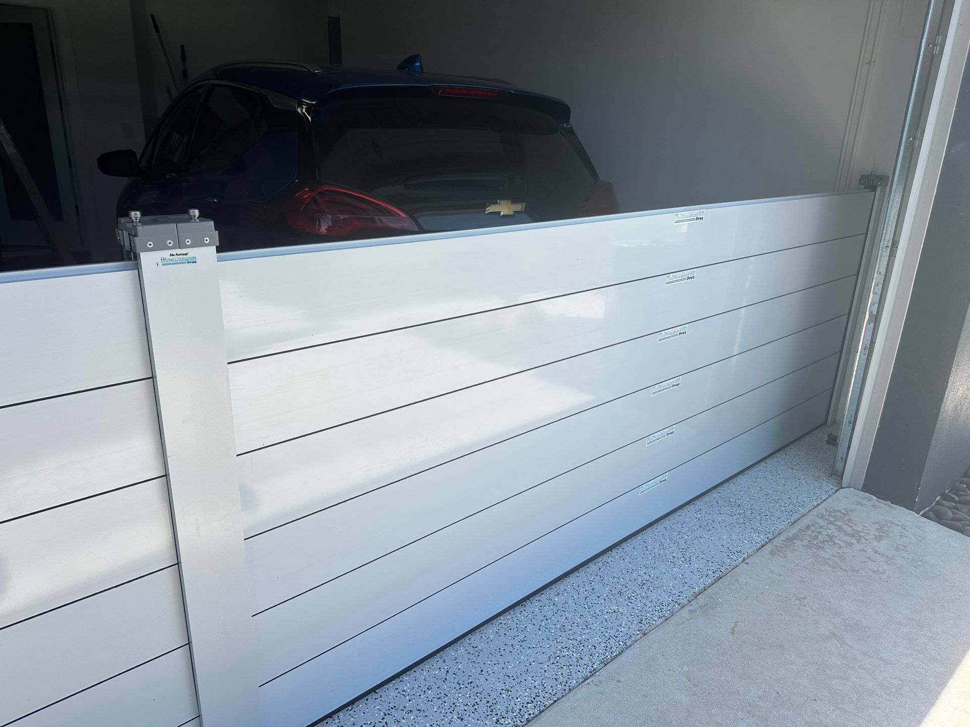 A car is parked in a garage behind a white barrier.