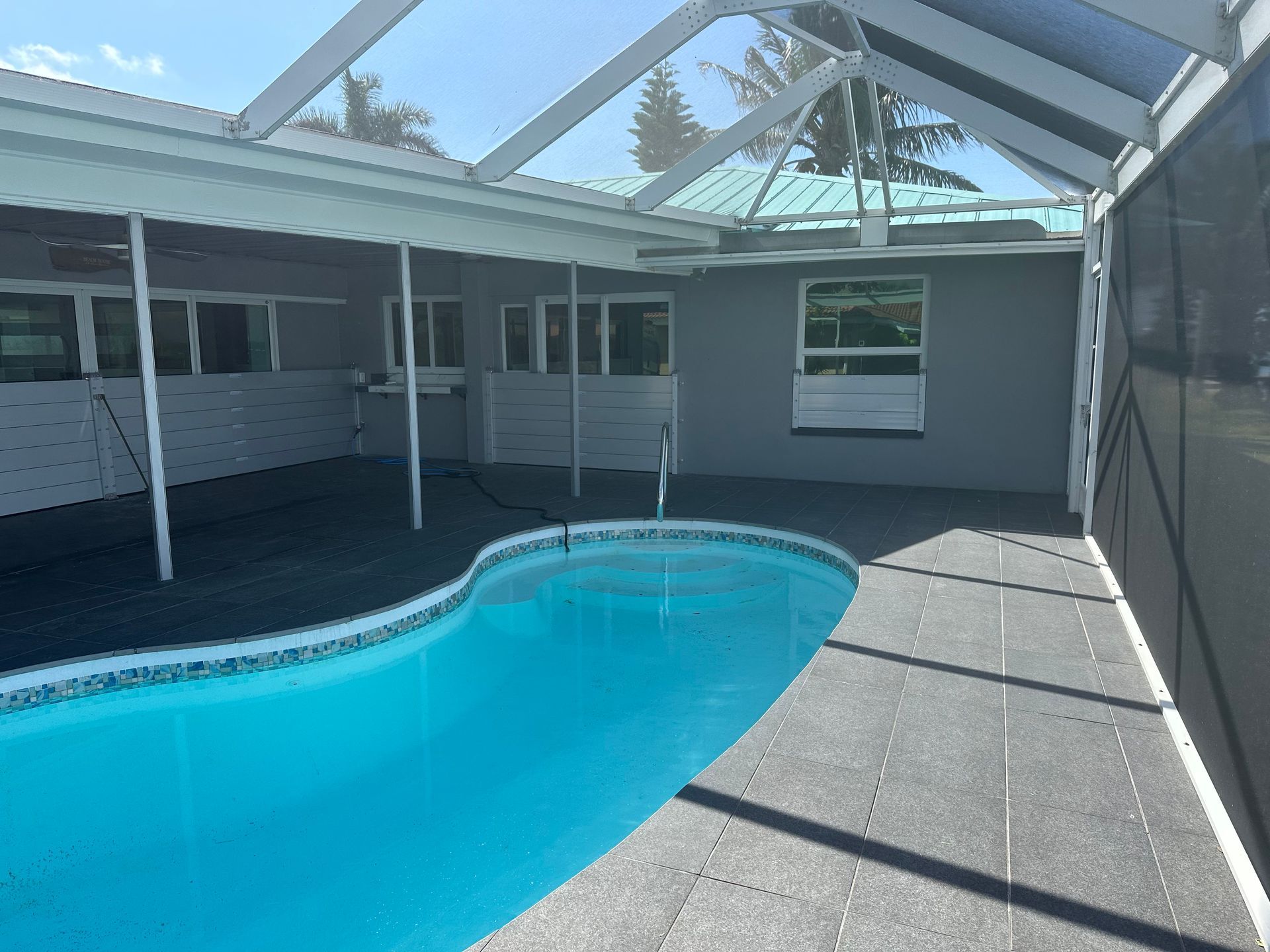 There is a large swimming pool in the backyard of a house.