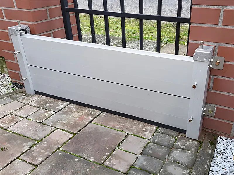 A white flood barrier is sitting next to a brick wall.