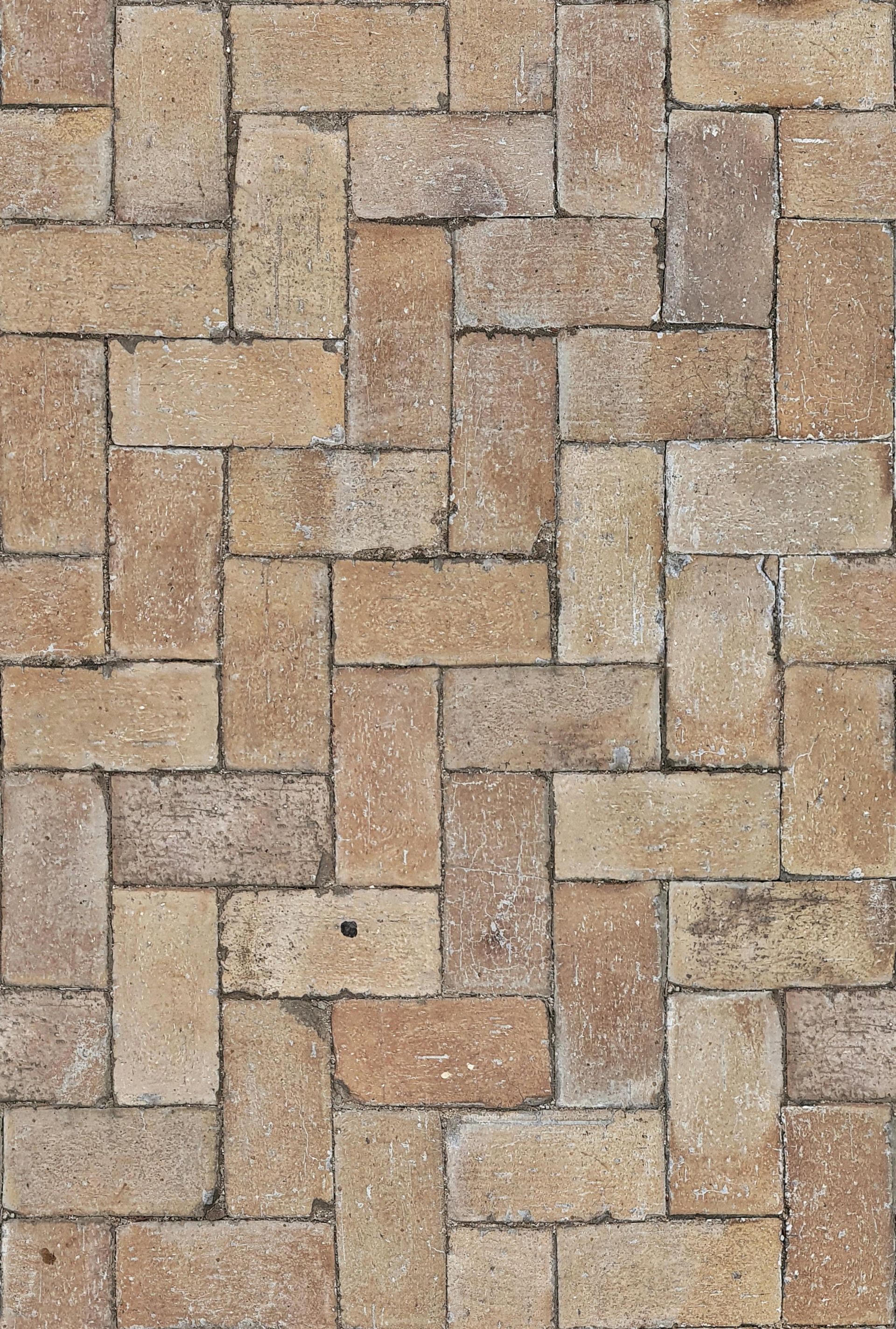 Brick paving in a herringbone pattern, various shades of tan and brown.