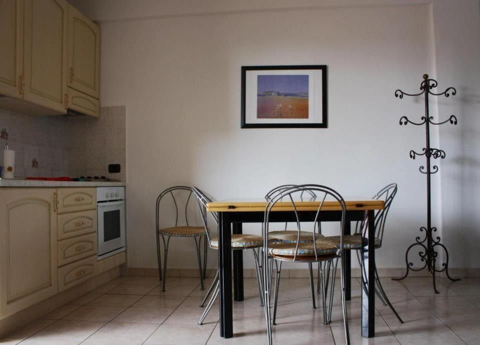 Piccola cucina e zona pranzo con tavolo e sedie, un quadro incorniciato e un attaccapanni.