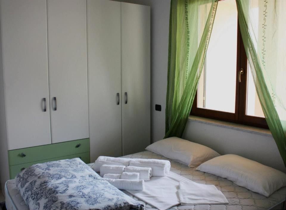 Camera da letto con armadio bianco, letto matrimoniale e tende verdi.