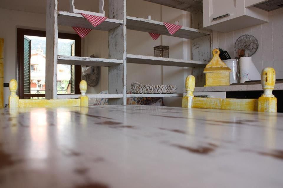 Cucina bianca con tavolo rustico e scaffali aperti, decorata con striscioni triangolari rossi e bianchi.