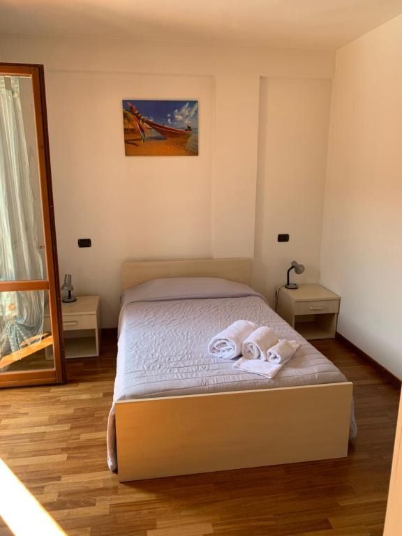 Camera da letto con letto singolo, comodini, quadro e finestra con cornice in legno.