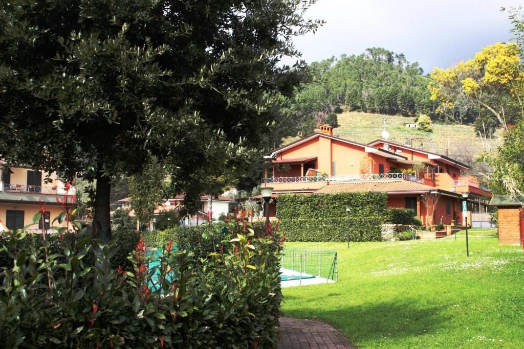 Edificio con tetto rosso immerso nel verde, con prato, alberi e una collina in lontananza.