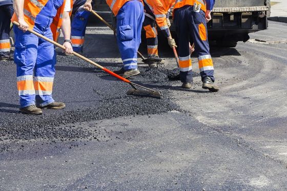 Workers on asphalting paver machine during road street repairing works in NC