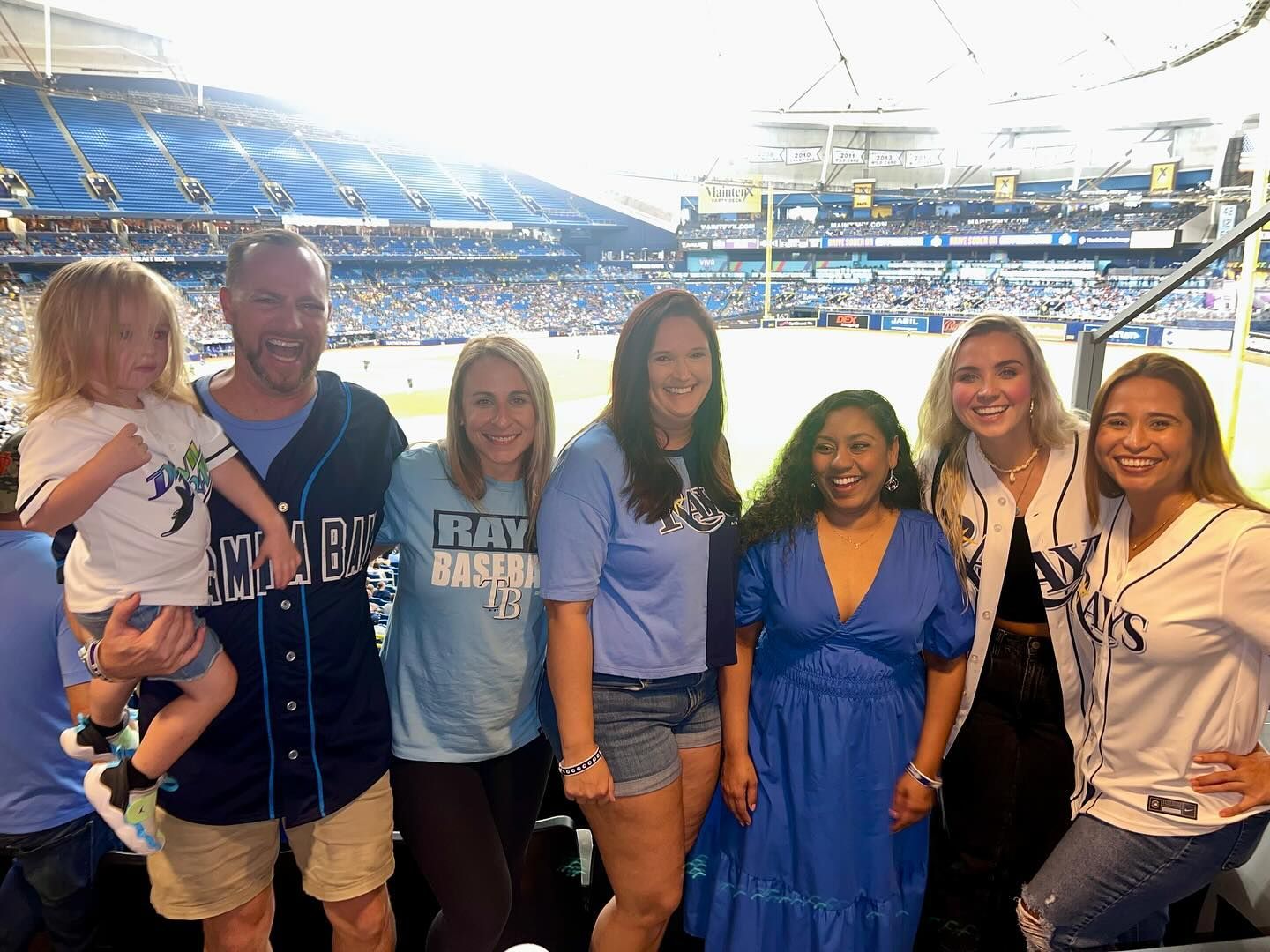 A group of people are posing for a picture in a baseball stadium.