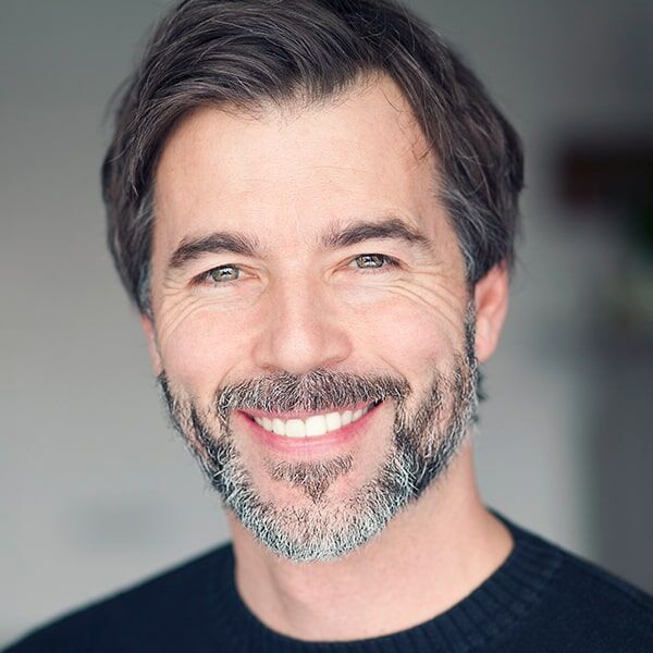 A man with a beard and mustache is smiling for the camera.