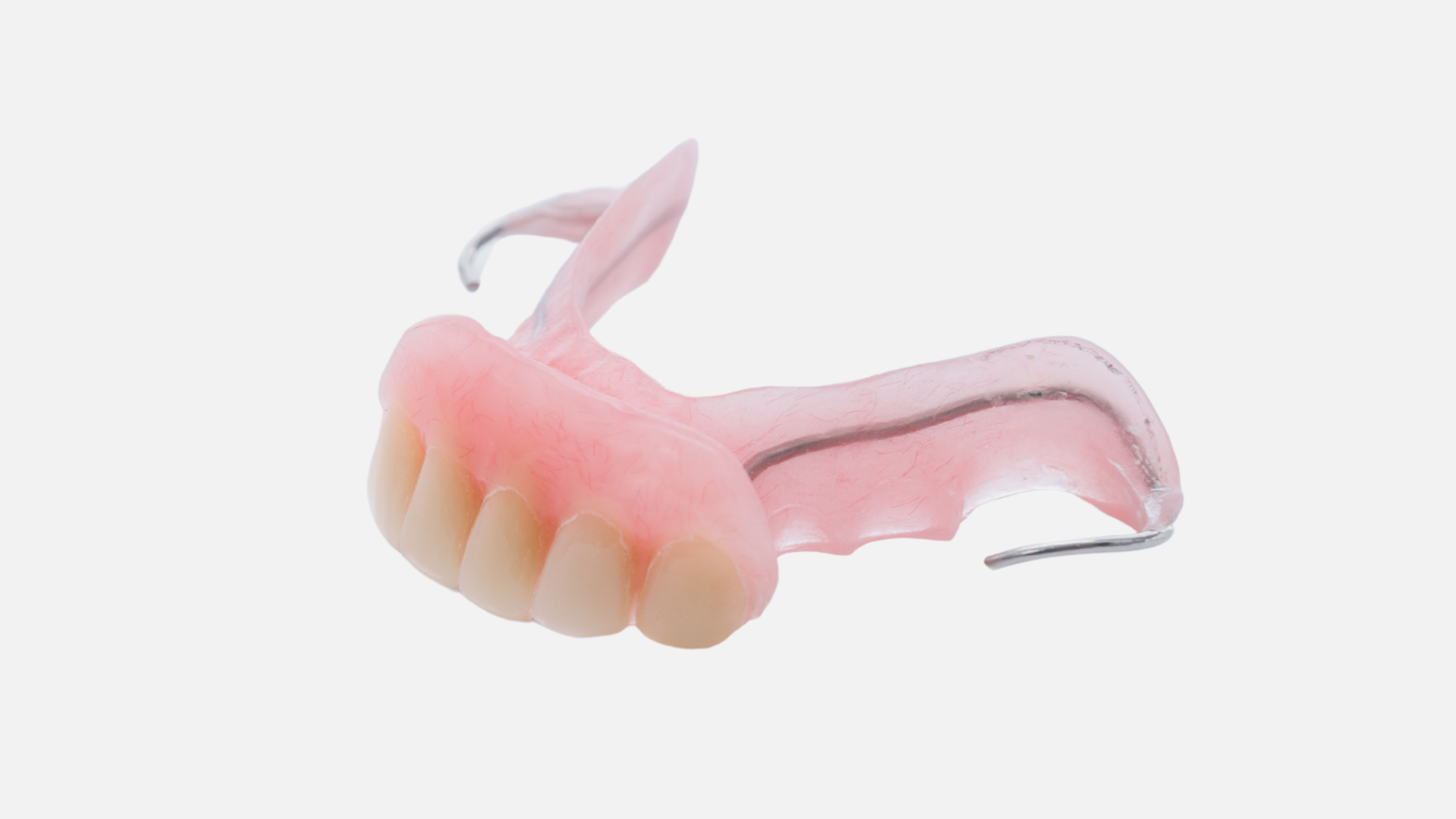 A close up of a pink denture on a white background.