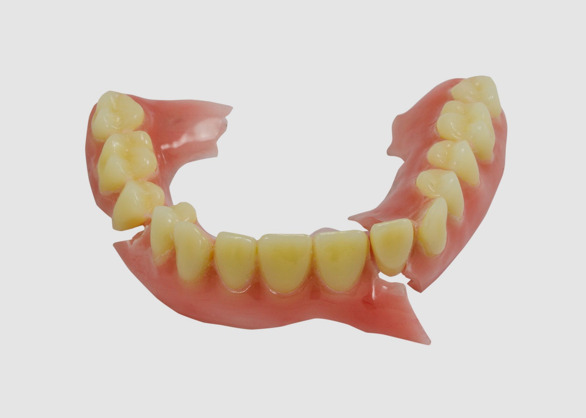 A broken denture with yellow teeth on a white background