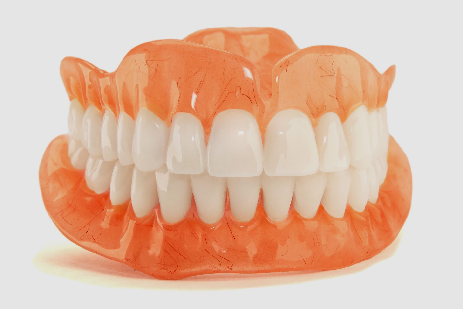 A close up of a full denture with white teeth on a white background.