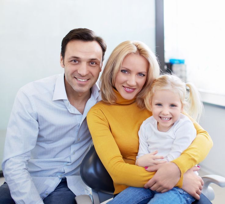 A family is posing for a picture while sitting in a dental chair