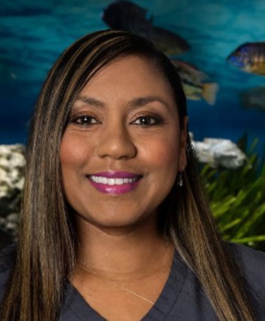 A woman is smiling in front of a fish tank.