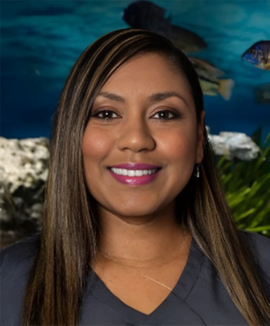 A woman is smiling in front of a fish tank.