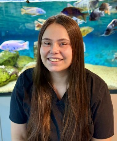 A woman is smiling in front of a fish tank.