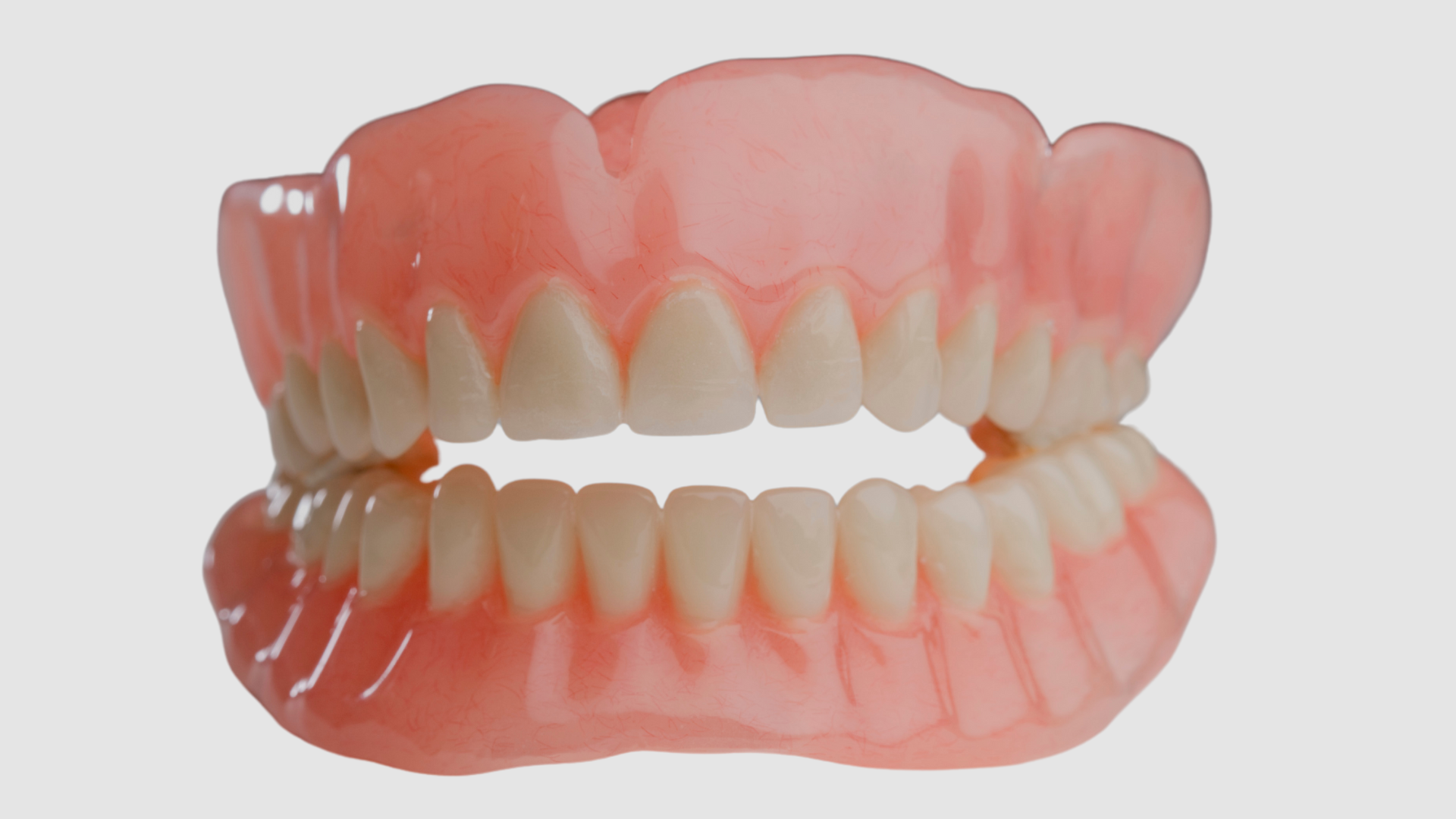 A close up of a denture with white teeth on a white background.