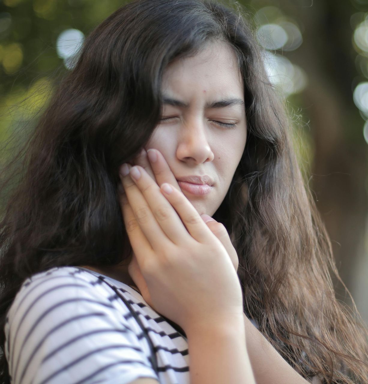A woman with long hair is covering her mouth with her hand