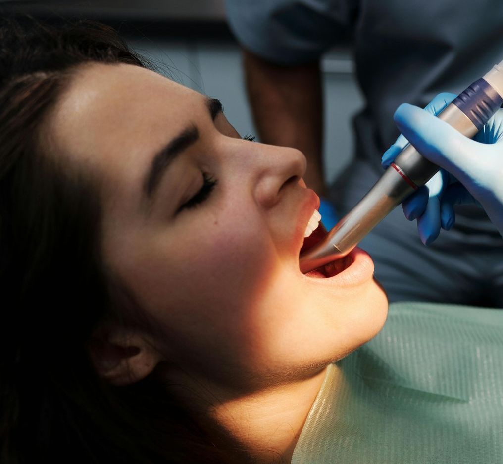 A woman is getting her teeth examined by a dentist