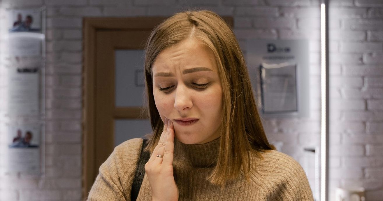 A woman is holding her face in pain because she has a toothache.